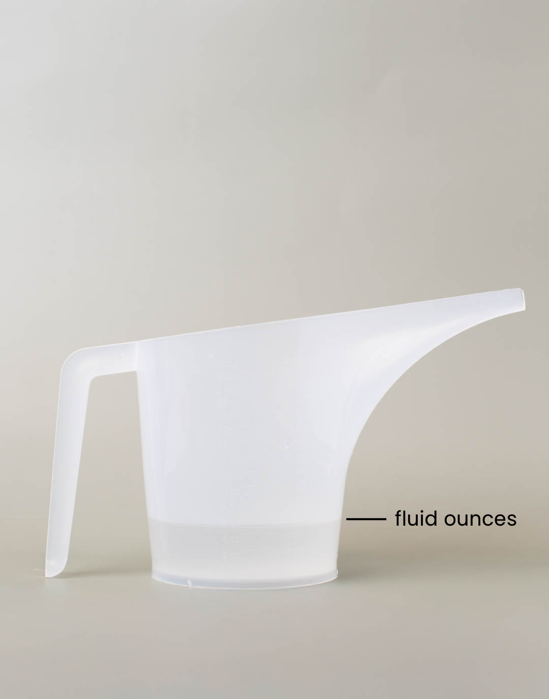 A mixture of fragrance a reed diffuser base in a funnel pouring pitcher with a line showing where the fluid ounce measurement is.